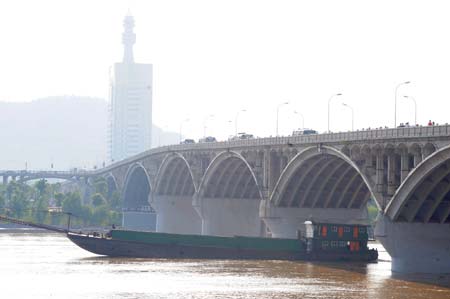  A boat passes under a bridge on the Xiangjiang River in Changsha, capital of central China's Hunan Province, July 3, 2009. Due to heavy rainfall since June 28, the water level of Xiangjiang River reached 32.15 meters at 8:00 am on Friday, 3.85 meters under the alert level. (Xinhua/Long Hongtao) 