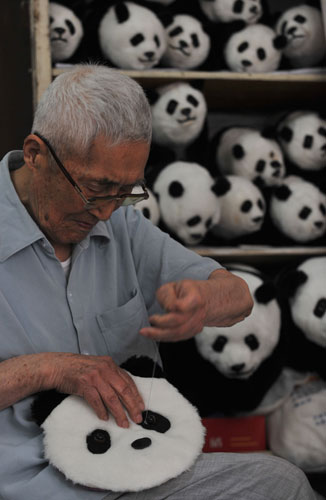 A 91-year-old citizen attaches eyes to a plush panda mask in a photo published on Thursday, July 2, 2009. The old craftman Liang is from Wuhan, capital of central China's Hubei Province. Liang and his student have manufactured over 1,000 handicrafts over the past year, including panda dolls, panda block prints, panda masks, panda badges, panda robes and other panda adornment accessories, all are favorably received in market. [Photo: CFP/Zhou Chao] 