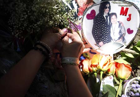 A fan places an item at a memorial for deceased pop star Michael Jackson outside the Jackson family home in Encino, California July 3, 2009.