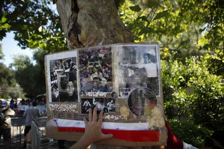 A fan puts up a cardboard sign by a memorial for deceased pop star Michael Jackson outside the Jackson family home in Encino, California July 3, 2009. 