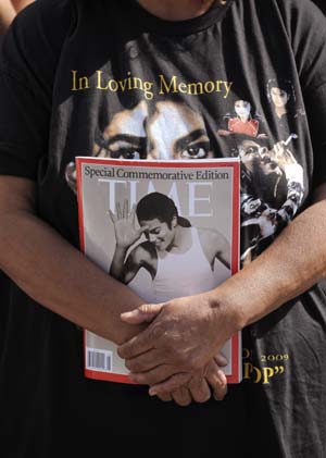 A fan holds a magazine across the street from a news conference announcing details of the Michael Jackson public memorial service in Los Angeles July 3, 2009. 