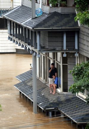 People wait for rescue on the platform of a building in the flood in Liuzhou, southwest China's Guangxi Zhuang Autonomous Region, July 4, 2009. Guilin, Hechi, Liuzhou, Laibin and Baise, cities in Guangxi Zhuang Autonomous Region, suffered the disaster of floods as torrential rains hit northwest and central Guangxi since June 30. The floods afflicted 914,500 people in Guangxi, according to the figures released on Saturday. (Xinhua/Huang Xiaobang)