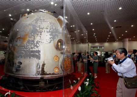 A visitor takes a shot of the re-entry module of Shenzhou VII spacecraft during the exhibition 'Roaming the Universe -- Aerospace Exhibition for China