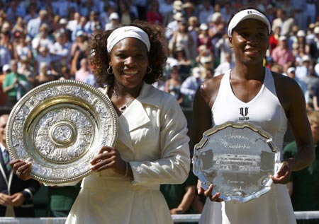 Serena Williams of the U.S. (L) holds her winners trophy and Venus Williams of the U.S. holds her runners-up trophy after their Ladies' Singles finals match at the Wimbledon tennis championships in London, July 4, 2009. Serena Williams clinched her third Wimbledon title and 11th Grand Slam crown with a 7-6 (7/3), 6-2 victory over sister Venus, the defending champion, on Saturday. [Xinhua/Reuters]