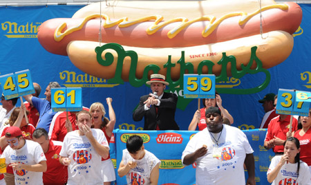 Contestants compete during the Nathan's annual hot dog eating contest in the Coney Island section of New York July 4, 2009. Joey Chestnut (2nd L) from California and Takeru Kobayashi (3rd L) of Japan won the first and second places by eating 68 and 64 hot dogs within 10 minutes during the contest on Saturday. [Xinhua]