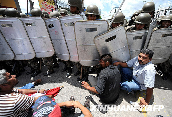 Supporters of ousted Honduras President Manuel Zelaya sit in front of a line of advancing soldiers at the international airport in Tegucigalpa July 5, 2009.[Xinhua/AFP]