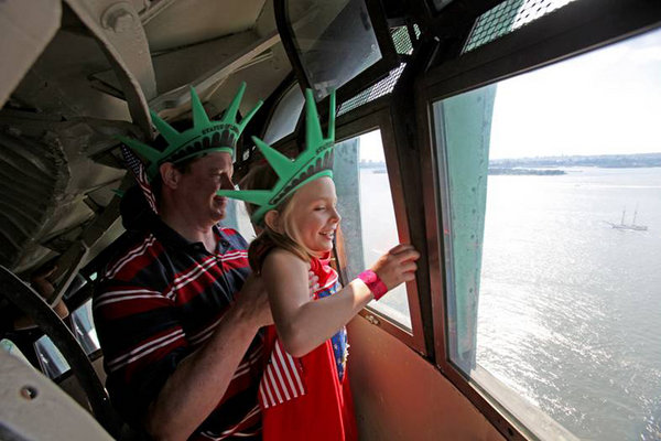 Chris Bartnick (L), 46, hoists his daughter Aleyna, 8, both of Merrick, New York, for a better view from the crown of the Statue of Liberty in New York City on July 4, 2009. 