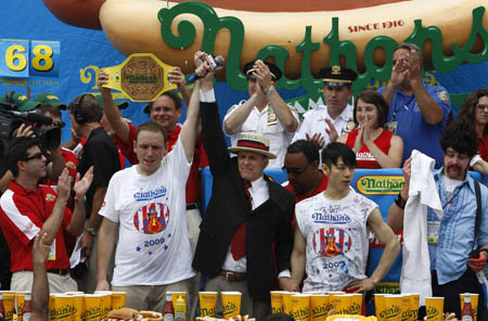 Joey Chestnut (2nd L) is announced the winner over Takeru Kobayashi of Japan (2nd R) at Nathan's annual hot dog eating contest in the Coney Island section of New York July 4, 2009. Chestnut set a world record by eating 68 hot dogs in 10 minutes. [Xinhua/Reuters]