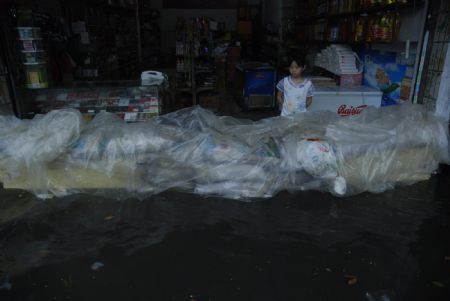 A girl watches a dam built with goods in front of a shop to resist the flood in downtown Yingtan city in southern China's Jiangxi Province, July 4, 2009. Heavy rain and storm struck the city Saturday paralysing part of the city's communications. [Hu Nan/Xinhua]