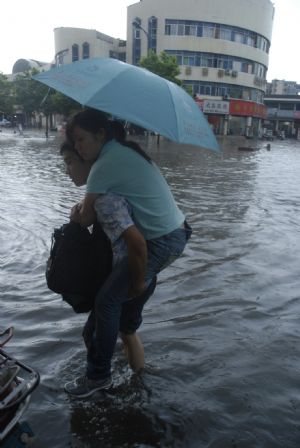 A local young couple manages their way in the flood in downtown Yingtan city in southern China's Jiangxi province, July 4, 2009. Heavy rain and storm struck the city Saturday paralysing part of the city's communications. [Hu Nan/Xinhua]