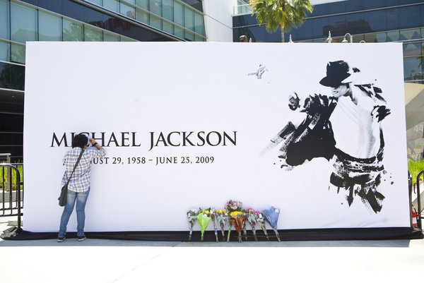 Lupe Garcia (left), 14, is one of the first to sign a large canvas print of Michael Jackson located in front of the Staples Center, where the Michael Jackson public memorial service will be held on Tuesday July 7, 2009 at the Staples Center. 