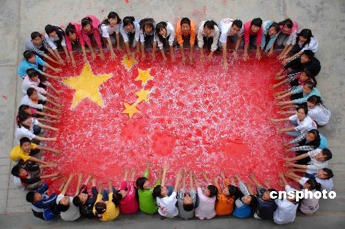 More than 300 middle school students in Lixian County, one of the Wenchuan earthquake-effected areas in northwest China's Gansu Province, and volunteers from Yangzhou University in eastern China's Jiangsu Province paint a big national flag with their hands on July 6, 2009. The 5.6-meter-long and 3.2-meter-wide flag is their special gift for the upcoming 60th anniversary of the founding of the People's Republic of China. [Cnsphoto]