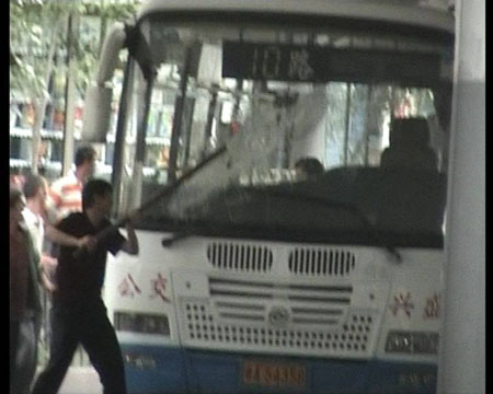 Photo released by police shows a rioter smashing a bus in Urumqi, capital of northwest China's Xinjiang Uygur Autonomous Region on July 5, 2009. [chinadaily.com.cn]