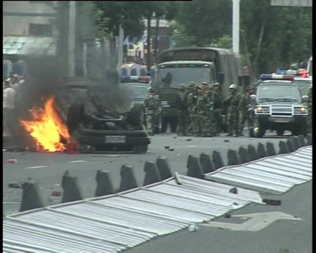 Photo released by police shows police vehicles hampered by a flaming car in Urumqi, capital of northwest China's Xinjiang Uygur Autonomous Region on July 5, 2009. [chinadaily.com.cn]