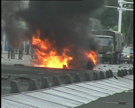 Photo released by police shows police vehicles hampered by a flaming car in Urumqi, capital of northwest China's Xinjiang Uygur Autonomous Region on July 5, 2009. [chinadaily.com.cn]