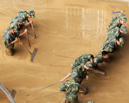 Soldiers help to clean up a silt-filled street after floods hit Liuzhou city, southwest Guangxi Zhuang autonomous region, on July 6, 2009. [Xinhua] 