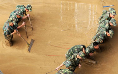 Soldiers help to clean up a silt-filled street after floods hit Liuzhou city, southwest Guangxi Zhuang autonomous region, on July 6, 2009. [Xinhua]