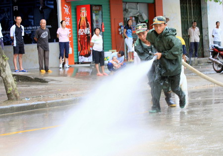 Two firefighters hose down a street in Rongshui county after floods hit the area in Guangxi Zhuang autonomous region on July 5, 2009. [Xinhua]