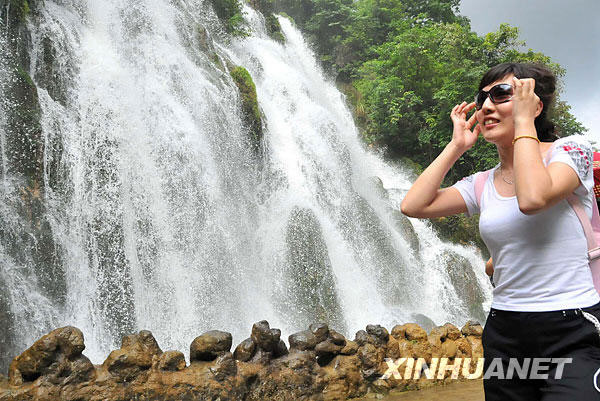 A girl enjoys herself beside a waterfall in the scenic spot of Libo Small Seven Holes in Guizhou province. Libo Small Seven Holes Scenic is named after the old seven holes bridge, which is listed as a world natural heritage site. Rain has been falling frequently here over recent days. While the traffic slows, the rivers quicken, adding some freshness to Libo's beauty. Photo published on Sunday, July 5, 2009. [Photo: Xinhuanet.com]