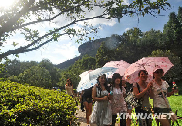 A group of tourists are seen strolling at the foot of Dawang Mountain in a photo issued on July 6, 2009. Dawang Mountain is a part of the Wuyi Mountain scenic area in Fujian Province, which has been listed as a world natural and cultural heritage site. It also includes Shennv Mountain and Jiuqu stream. The scenic area receives more than 10,000 tourists a day during the summer. [Photo: Xinhuanet.com]