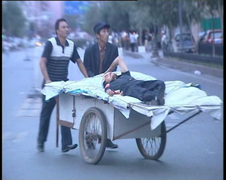 Photo released by police shows two citizens carrying a wounded person in Urumqi, capital of northwest China&apos;s Xinjiang Uygur Autonomous Region on July 5, 2009. [chinadaily.com.cn]