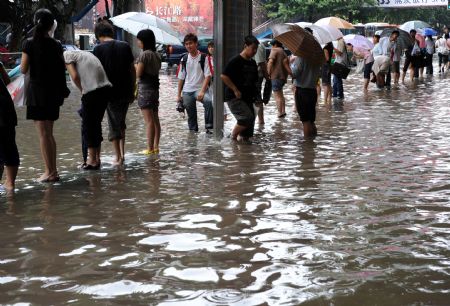 Citizens wait for bus on the flooded road in Nanjing, capital of east China's Jiangsu Province, July 7, 2009. A heavy downpour drenched the city and blocked the traffic from Monday night to Tuesday morning. [Sun Can/Xinhua]