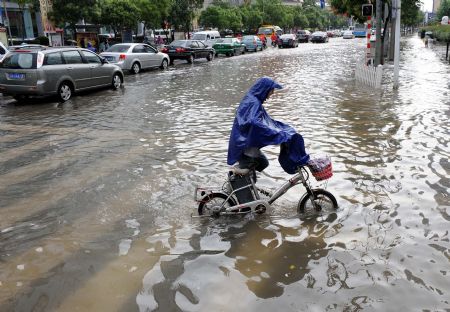 A citizen wades on the flooded road in Nanjing, capital of east China's Jiangsu Province, July 7, 2009. A heavy downpour drenched the city and blocked the traffic from Monday night to Tuesday morning. [Sun Can/Xinhua]