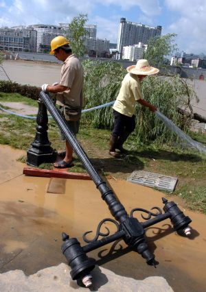 Two electricians repair the street lights destroyed during the flood along the Liujiang River in Liuzhou City of southwest China's Guangxi Zhuang Autonomous Region, July 7, 2009. The flood passing through Liujiang River receded on July 6 and local people began to clean the city and restore the basic facilities. [Lai Liusheng/Xinhua]