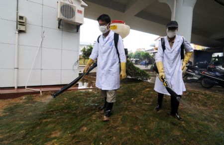 Two epidemic prevention workers sterilize the city after the flood receded in Liuzhou City of southwest China's Guangxi Zhuang Autonomous Region, July 7, 2009. The flood passing through Liujiang River receded on July 6 and local people began to clean the city and restore the basic facilities. [Li Bin/Xinhua]