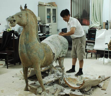 An archaeologist demoulds the bronze horse sculpture in Xiangfan City of central China's Hubei Province, July 7, 2009. Unearthed at the end of 2008 from a tomb of Wei or Jin Dynasties, dating back 1,700 years, only the front part of the bronze horse was found in integrity while the back in pieces. After seven months' restoration, the archaeologists have reshaped the bronze horse and demoulded the sculpture successfully on Tuesday. (Xinhua/An Fubin) 