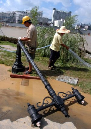 Two electricians repair the street lights destroyed during the flood along the Liujiang River in Liuzhou City of southwest China's Guangxi Zhuang Autonomous Region, July 7, 2009. The flood passing through Liujiang River receded on July 6 and local people began to clean the city and restore the basic facilities. (Xinhua/Lai Liusheng)