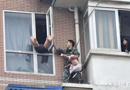 Firefighter Chen Long grabs a two-year-old girl from her father, Hu Binjun, who allegedly took drugs before attempting to commit suicide with his child by jumping from a window in Chengdu, Sichuan Province, on Tuesday. [China Daily]