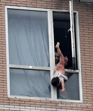 Hu Binjun is seen trying to commit suicide with his child by jumping from a window in Chengdu, Sichuan province, on Tuesday, July 7, 2009. [Asianewsphoto] 