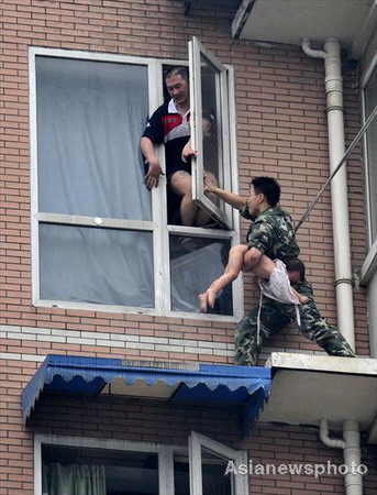 A firefighter grabs a two-year-old girl from her father, Hu Binjun, who allegedly took drugs before attempting to commit suicide with his child by jumping from a window in Chengdu, Sichuan province, on Tuesday, July 7, 2009.[Asianewsphoto] 