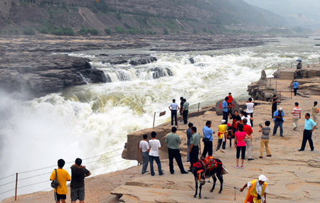 Visitors view and admire the limpid Hukou Waterfall on the Yellow River at Jixian County, north China's Shanxi Province, July 7, 2009. [Yan Ruipeng/Xinhua]