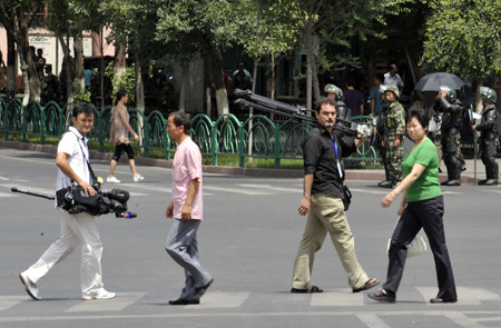 Overseas journalists carrying equipment walk on a street in Urumqi, capital of northwest China's Xinjiang Uygur Autonomous Region, July 8, 2009. [Shen Qiao/Xinhua]