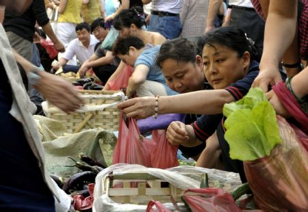 People buy vegetables at a market in Urumqi, capital of northwest China's Xinjiang Uygur Autonomous Region, on July 8, 2009. Urumqi appeared to be calm under heavy paramilitary police presence Wednesday after an overnight traffic curfew, but sporadic standoffs and clashes were still reported. [Xinhua]