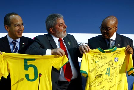 Mexican President Felipe Calderon (L) and President of South Africa Jacob Zuma (R) show the uniforms of Brazilian national football team presented by Brazilian President Luiz Inacio Lula da Silva (C) after a joint press conference in L'Aquila, Italy, July 8, 2009. On behalf of Chinese President Hu Jintao, State Councilor Dai Bingguo attended the joint press conference with leaders of India, Brazil, South Africa and Mexico here on Wednesday. [Xinhua]