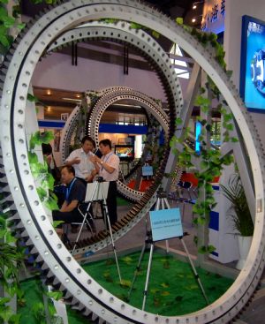 Visitors talk about an equipment on display during the 6th Asian Wind Energy Exhibition in Beijing, capital of China, on July 8, 2009. The exhibition, attended by 445 enterprises from 22 countries and regions, kicked off here Wednesday. [Gong Lei/Xinhua]
