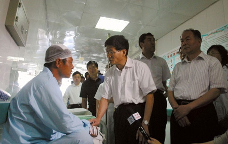 Meng Jianzhu (C), China's state councilor and public security minister, visits a man injured in the July 5 riot, at the People's Hospital of Xinjiang Uygur Autonomous Region in Urumqi, capital of the region in northwest China, July 8, 2009.
