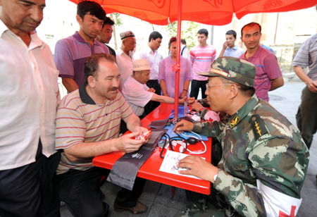 Residents consult a medical member of the Armed Police during a community free medical service at a street in Urumqi, capital of northwest China's Xinjiang Uygur Autonomous Region July 9, 2009. [Xinhua]