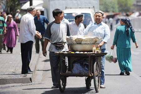 A vendor sells food in the Erdaoqiao area in Urumqi, capital of northwest China's Xinjiang Uygur Autonomous Region, July 9, 2009. Shopping malls, supermarkets, agricultural product markets and gas stations are resuming business in the riot-torn Urumqi. [Xinhua]