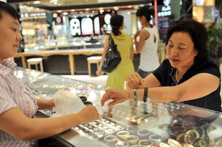 A customer (R) selects jewelry at the Wangfujing shopping mall in Urumqi, capital of northwest China's Xinjiang Uygur Autonomous Region, July 9, 2009. Shopping malls, supermarkets, agricultural product markets and gas stations are resuming business in the riot-torn Urumqi. [Xinhua]
