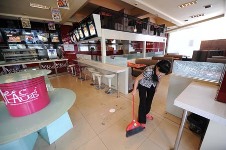 An employee cleans a restaurant in the Erdaoqiao area in Urumqi, capital of northwest China's Xinjiang Uygur Autonomous Region, July 9, 2009. Shopping malls, supermarkets, agricultural product markets and gas stations are resuming business in the riot-torn Urumqi. [Xinhua]