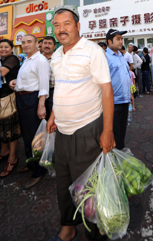 A resident buys vegetables at the Erdaoqiao market in Urumqi, capital of northwest China&apos;s Xinjiang Uygur Autonomous Region July 9, 2009. The local business administration distributed tens of railway wagons of vegetables to fully supply the city on Thursday. 