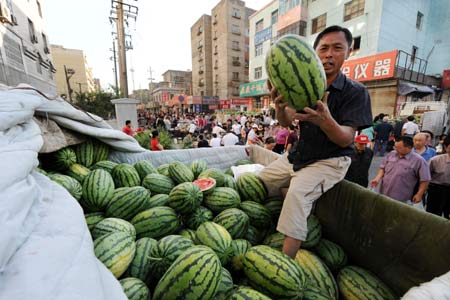 A vender sells watermelons at a market in Urumqi, capital of northwest China's Xinjiang Uygur Autonomous Region, on the morning of July 10, 2009. [Xinhua]