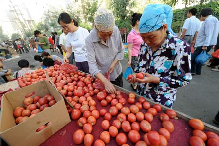 Residents select tomatoes at a market in Urumqi, capital of northwest China's Xinjiang Uygur Autonomous Region, on the morning of July 10, 2009. [Xinhua]