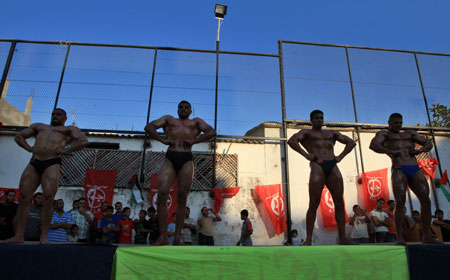 Palestinian bodybuilders display their skills in a locally organaized competition in al-Nussierat refugee camp, central Gaza Strip, on July 10, 2009. [Wissam Nassar/Xinhua] 