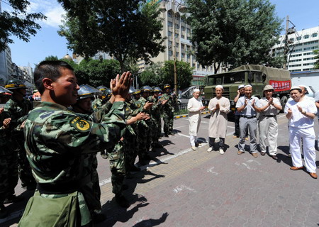 Public security forces acknowledge greetings from Islamic group members in Urumqi, northwest China's Xinjiang Uygur Autonomous Region, Friday July 10, 2009. [Xinhua]