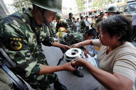 A woman gives self-prepared porridge to the public security forces whose intrepid presence spared the riot-plagued city from further unrests, in Urumqi, northwest China's Xinjiang Uygur Autonomous Region, Friday July 10, 2009. [Xinhua]